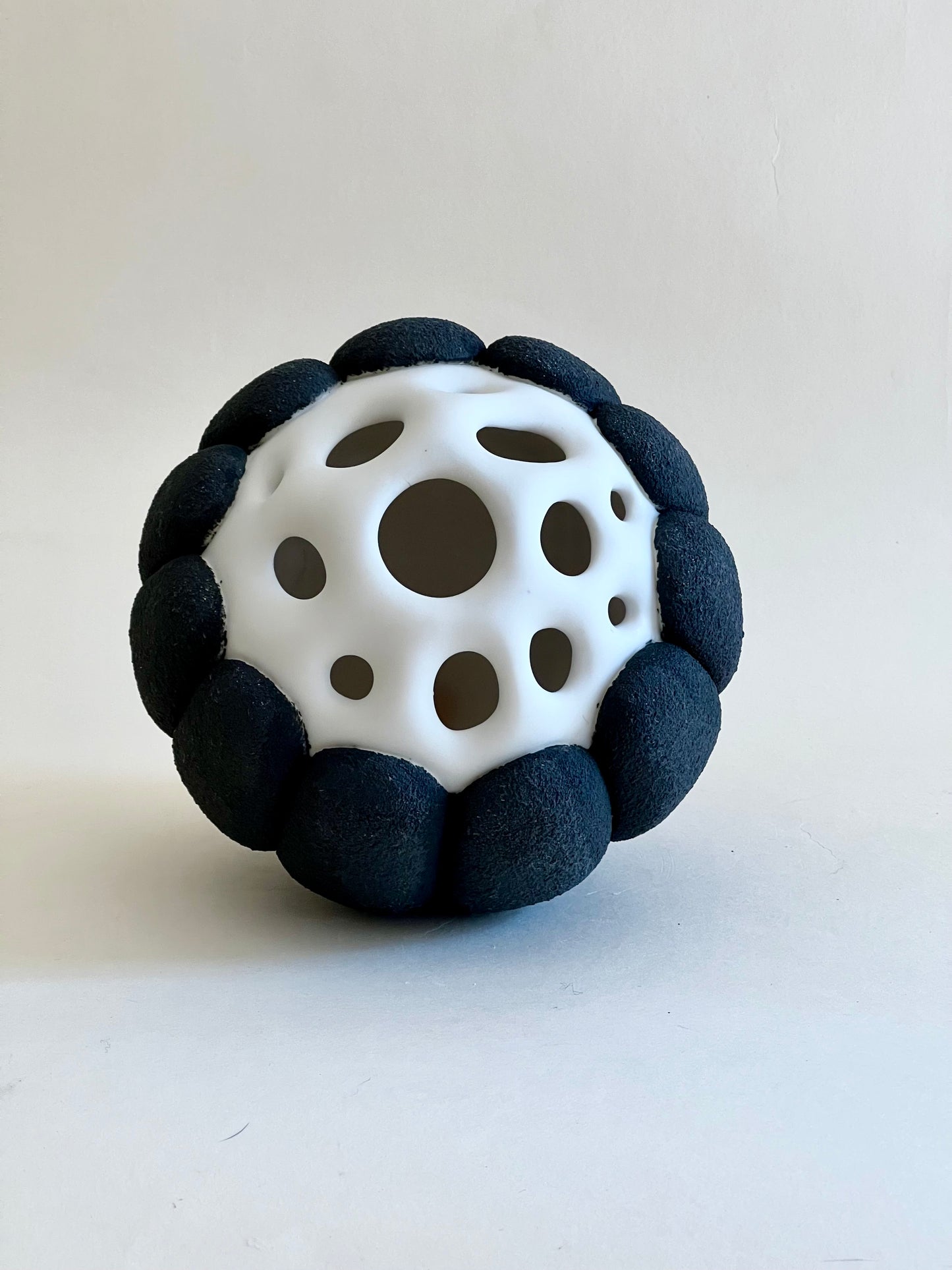 Front view of pierced porcelain sculpture inspired by organic seed forms.