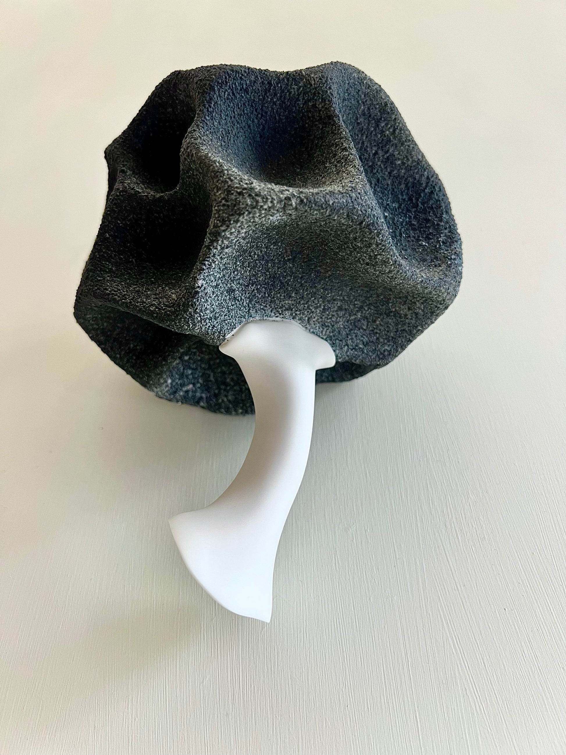 Bottom view of Crazy Wallflower — Black Spore, showing the smooth white porcelain stem and textured dark upper form.
