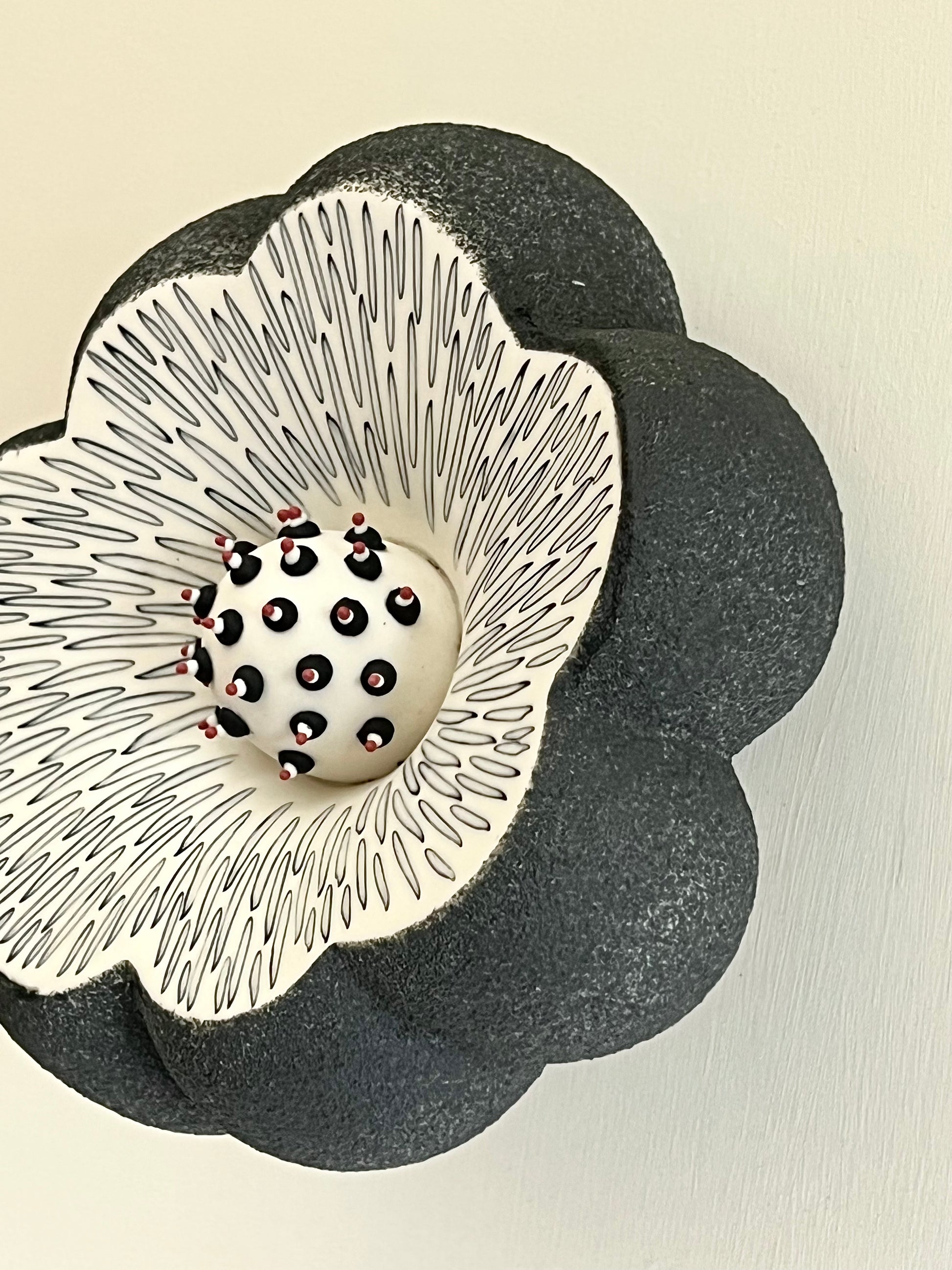Side view of Crazy Wallflower — Pollen showing the sculptural depth and textured black porcelain surface