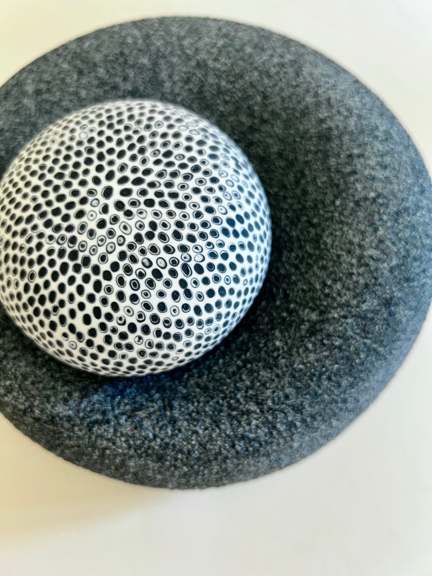Top view of handmade porcelain sphere covered with an intricate black and white porcelain inlay pattern.
