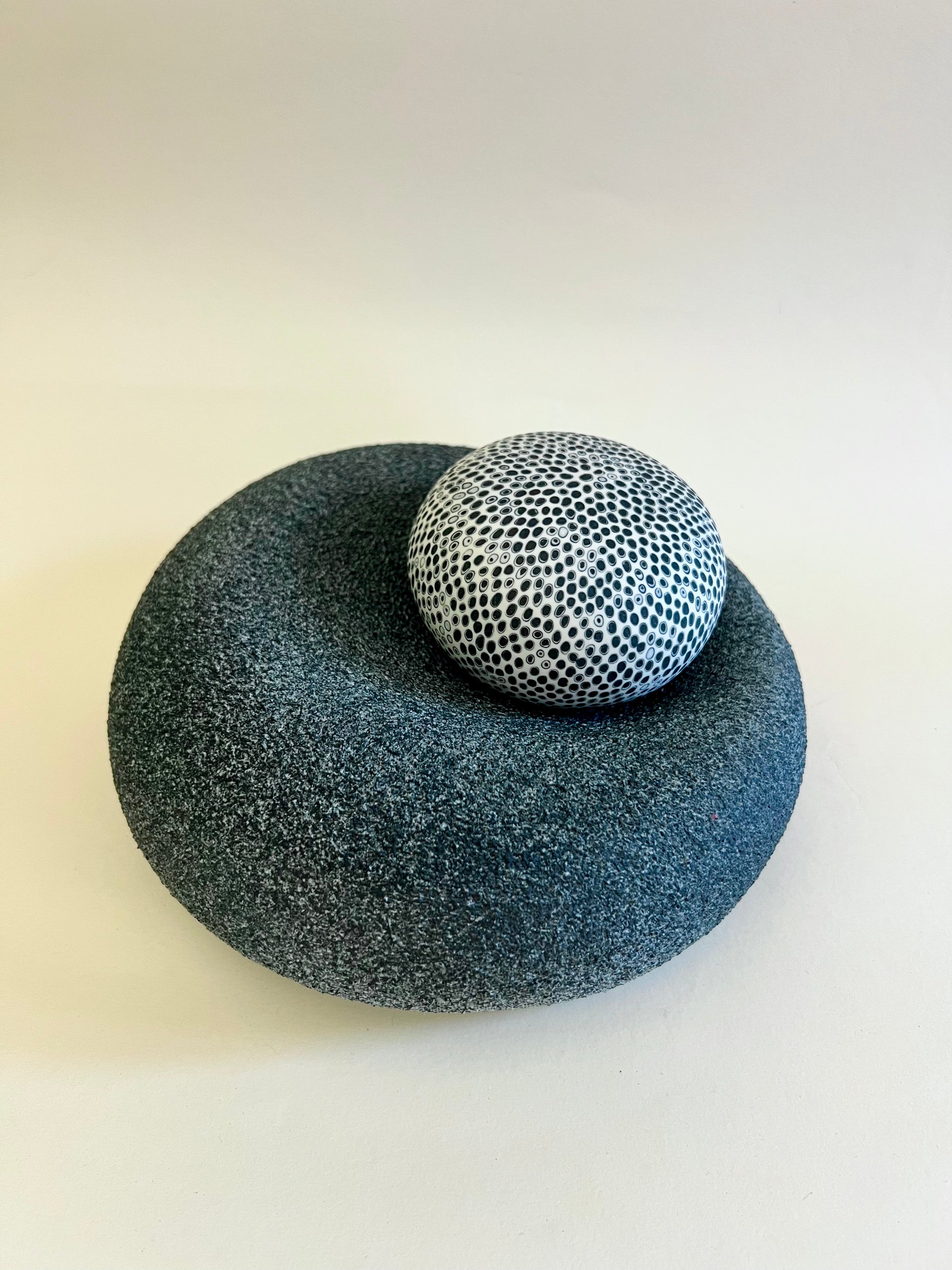 Contemporary porcelain sculpture featuring a hand-decorated sphere resting on a textured organic base.
