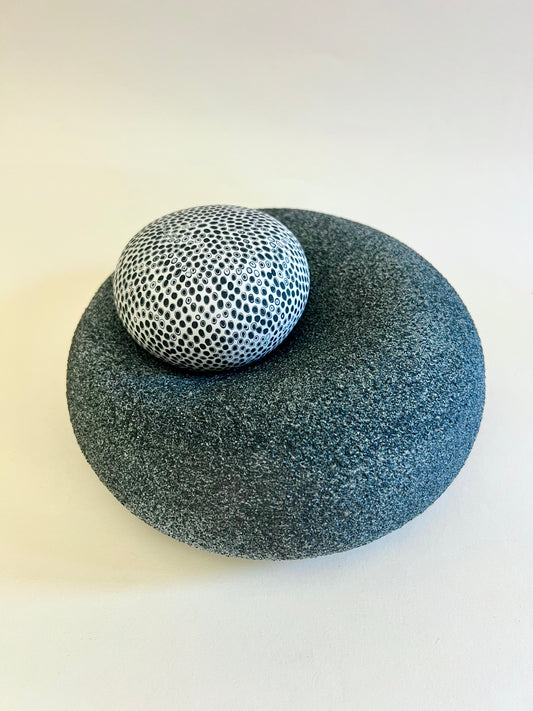 Handmade porcelain sculpture with textured black base and removable white porcelain sphere decorated with black inlay.