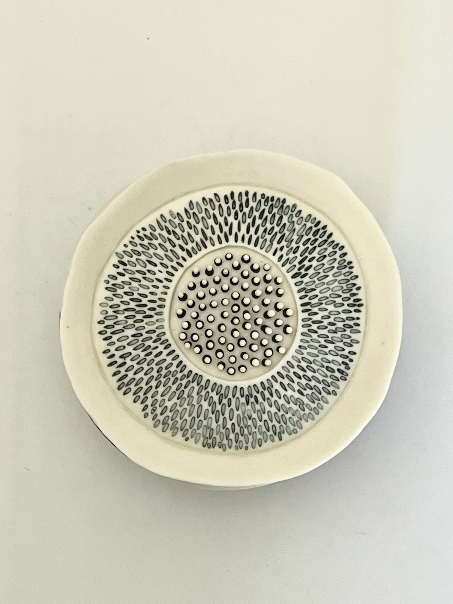 Pulse 1 porcelain sculpture viewed from above, showing the radiating black inlay pattern and central black and white detail