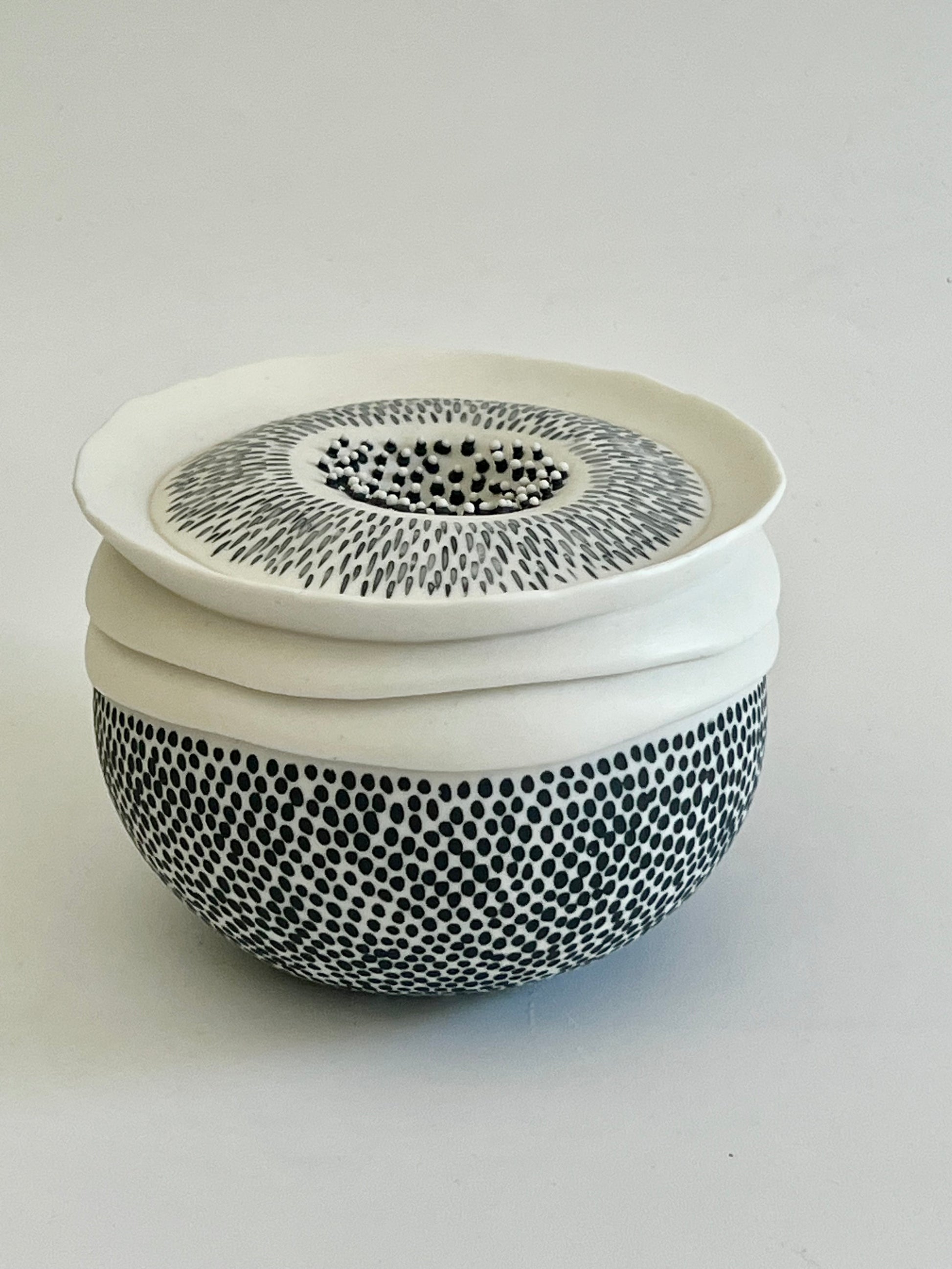 Pulse III, handmade white porcelain vessel, wheel-thrown and slightly altered by hand, featuring a black and white dotted surface and an organically shaped upper section.
