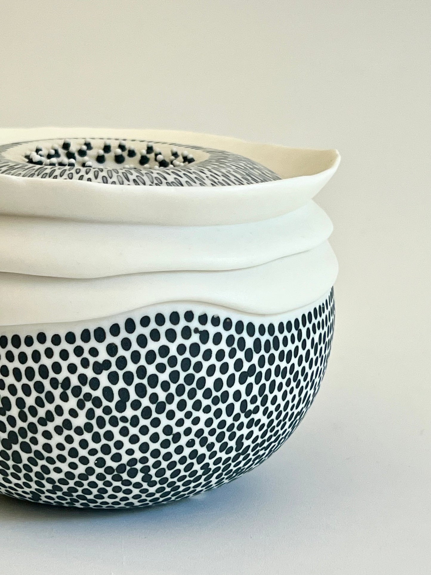 Close-up of the lower body of Pulse III showing the dense black dotted decoration applied to the white porcelain surface and the subtle variation in size and spacing of the marks.