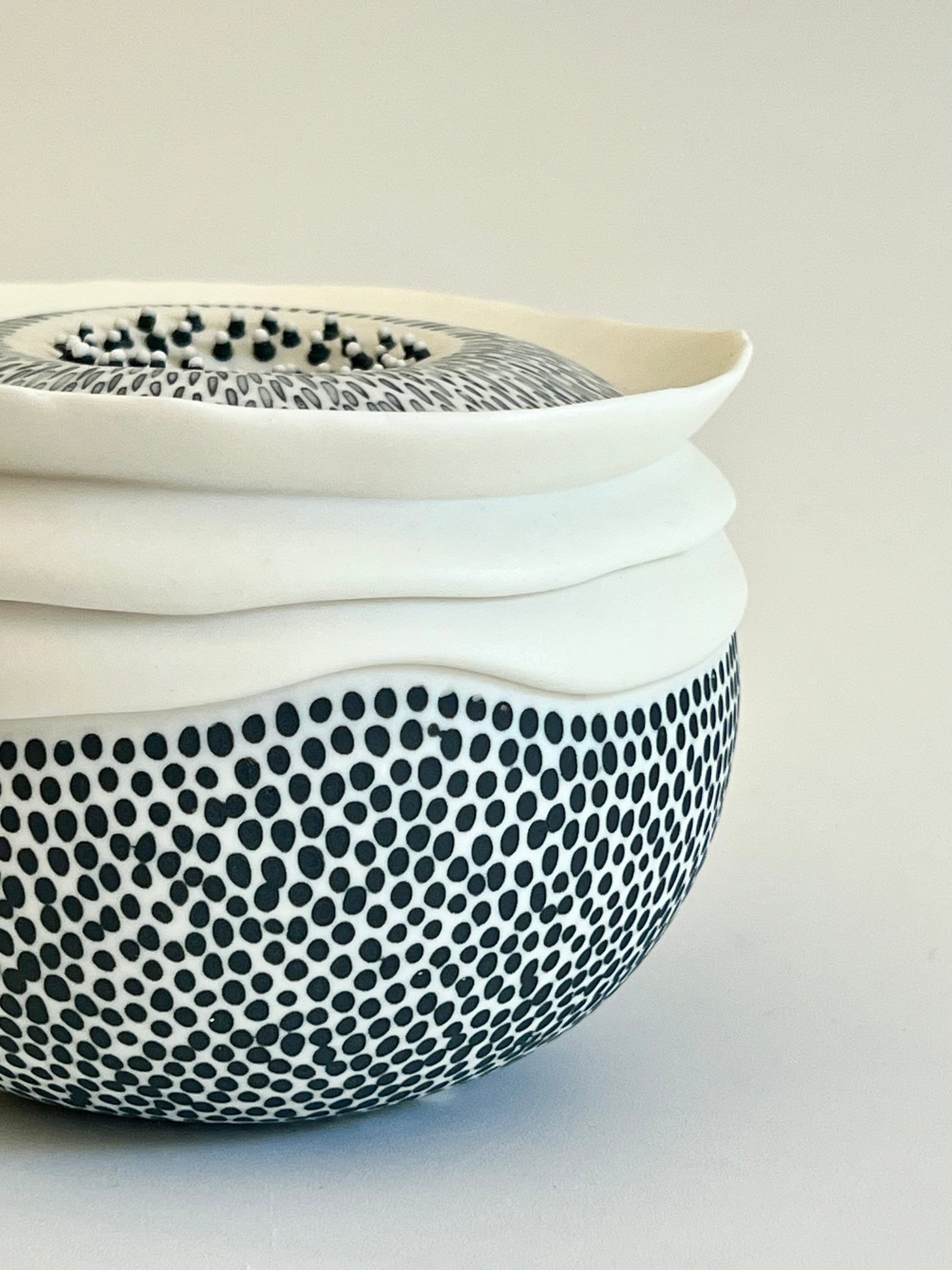 Close-up of the lower body of Pulse III showing the dense black dotted decoration applied to the white porcelain surface and the subtle variation in size and spacing of the marks.