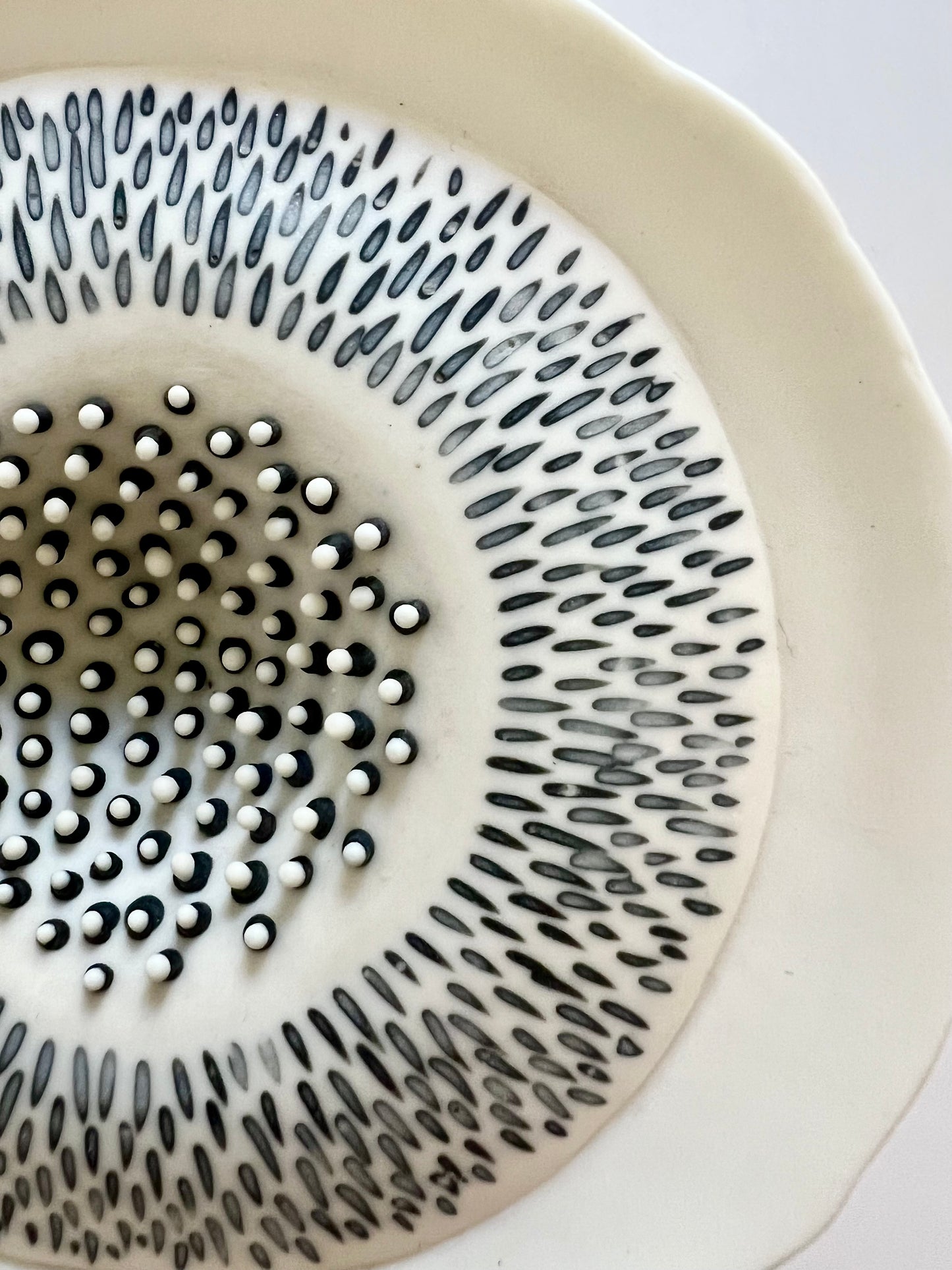 Close-up of the upper surface of Pulse III showing the hand-incised radial pattern and the contrasting raised black and white porcelain details at the centre.