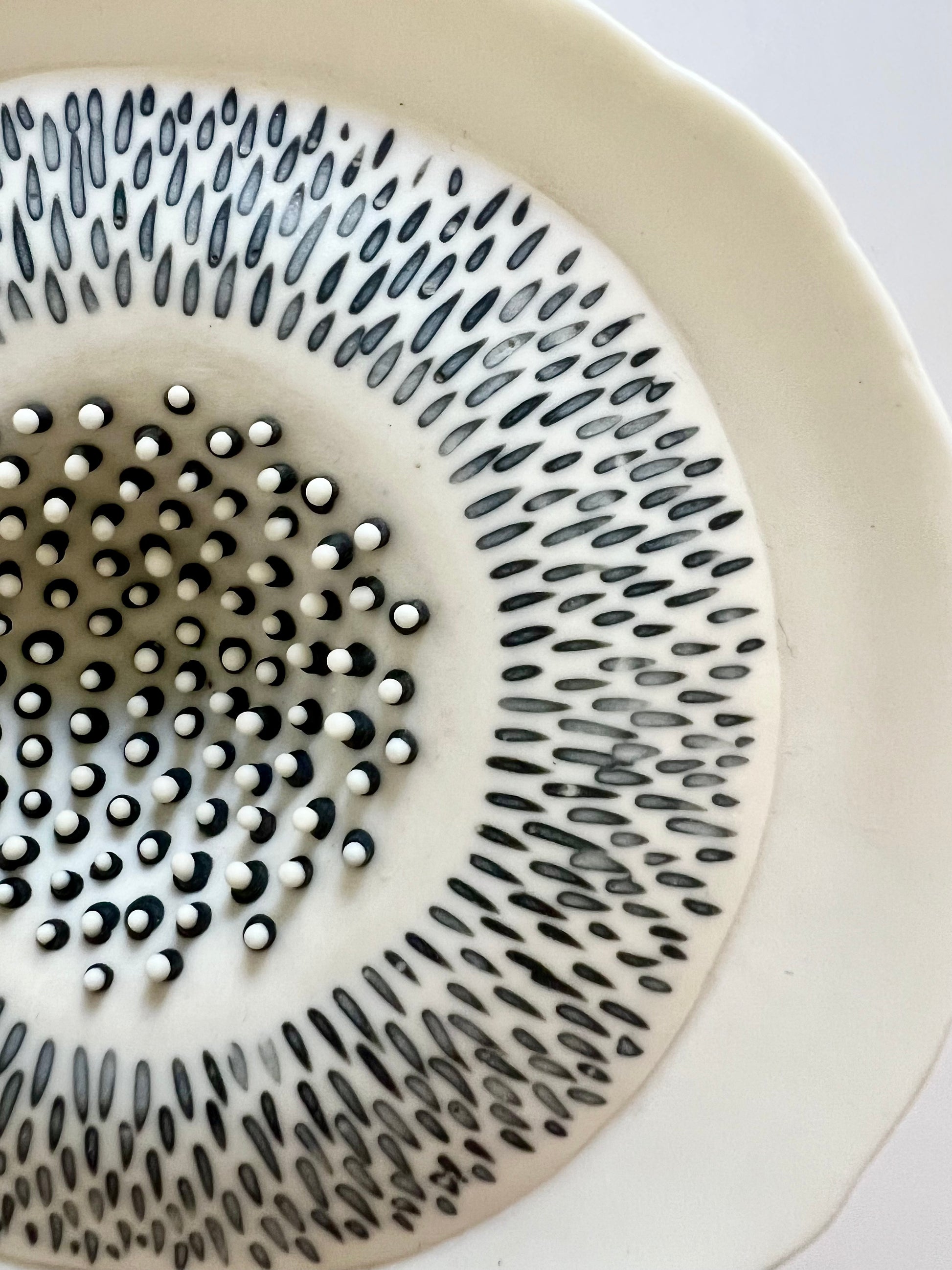 Close-up of the upper surface of Pulse III showing the hand-incised radial pattern and the contrasting raised black and white porcelain details at the centre.