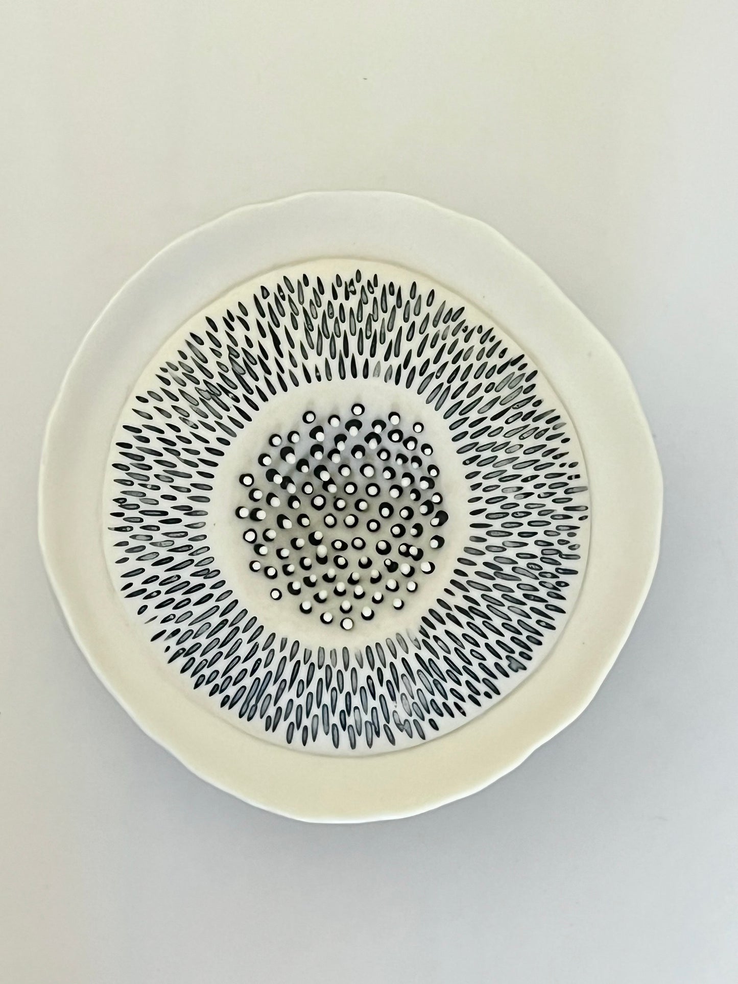 Top view of Pulse III showing the white porcelain rim, radial black and grey incised decoration and the central area with raised black and white porcelain details.
