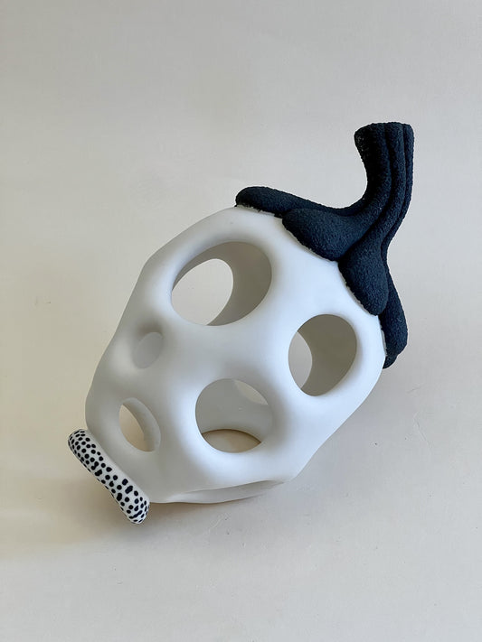 Handmade white porcelain sculpture with pierced organic form and textured black porcelain top.